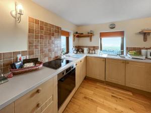 a large kitchen with wooden floors and a large window at Bothan Aonghais in Portree +6 photos