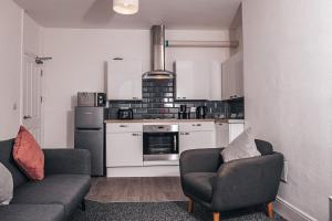 a living room with two chairs and a kitchen at STAYtastic in Lowestoft