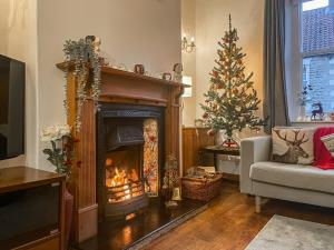 a living room with a fireplace and a christmas tree at The Swiss Cottage in Pickering