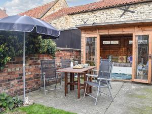 a patio with a table and chairs and an umbrella at The Swiss Cottage in Pickering +16 photos