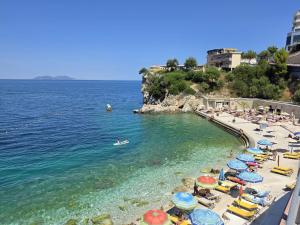 a beach with umbrellas and people in the water at Villa Meminaj in Vlorë