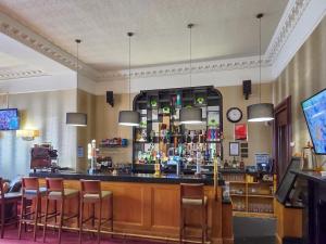 a bar in a restaurant with chairs and a clock at 1 Sunview Garden in Birnam