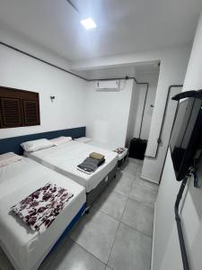 a room with two beds and a tv in it at Pousada beira mar e sol in Tibau