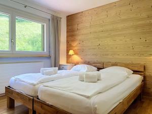 two beds in a bedroom with a wooden wall at Apartment Eden Roc 53 by Interhome in Nendaz