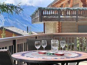 a table with wine glasses sitting on a balcony at Apartment Eden Roc 53 by Interhome in Nendaz