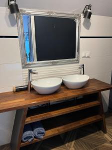 two white sinks on a wooden table with a mirror at Apartament Morgan in Mieroszyno
