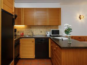 a kitchen with wooden cabinets and a black dishwasher at Studio Terrasse Des Alpes 615 by Interhome in Vermala +33 photos
