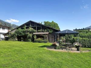 a house with an umbrella and a green yard at Apartment Appartements Binderhof-1 by Interhome in Aschau