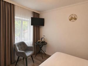 a room with a bed and a chair and a window at Silver Residence Brașov in Braşov