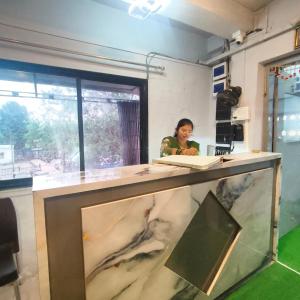 a woman standing behind a counter with a fish tank at Hotel My Home Dormitory in Boisar