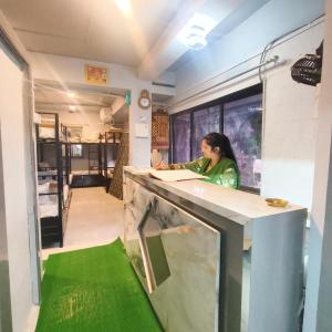 a woman standing at a counter in a kitchen at Hotel My Home Dormitory in Boisar