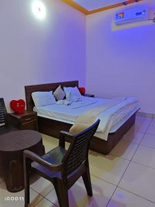 a bedroom with a bed and a chair and a table at Green Hotel in Jīnd