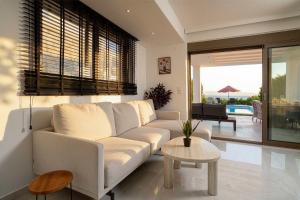 a living room with a white couch and a table at Villa Mare 2 - Private Pool, Sea View, Starlink, 4 Bdrms in Hanioti