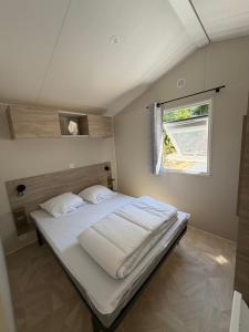 a bedroom with a large white bed with a window at Bahia 2 in Le Faulq