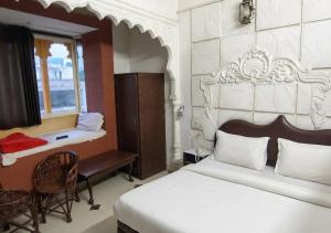 a bedroom with a bed and a desk and a window at Hotel Royal Palace in Chittaurgarh