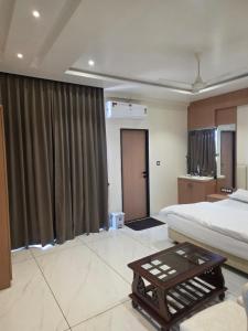a bedroom with a bed and a coffee table at Hotel Nandanwan Resto and Bar in Mālsiras