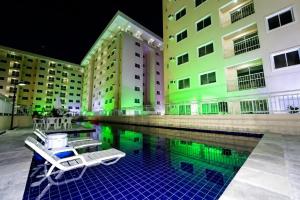 a swimming pool with two chairs in front of buildings at Quarto Nômade Digital in Aracaju