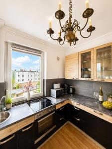 a kitchen with black cabinets and a large window at Velmora Boutique Suites - Vintage Design Apartment in Altstadtnähe in Lübeck