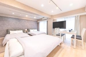 a bedroom with two beds and a desk and a television at ベルビー川崎 in Kawasaki