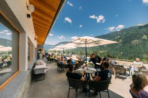 Eine Gruppe von Menschen sitzt an Tischen auf einer Terrasse in der Unterkunft Malga Prefaè in Commezzadura