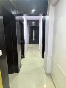 a hallway with black doors and a tile floor at Hotel keshav in Ahmedabad