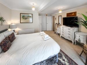 a bedroom with a large white bed and a flat screen tv at St Augustine's Stays - Stone Bay in Broadstairs +7 photos