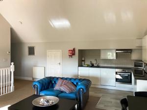 a living room with a blue couch and a kitchen at Periwinkle No5 - Uk49249 in Althorne