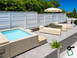 a swimming pool with chairs and an umbrella on a patio at Hotiday Apartments Cefalù in Cefalù