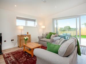 a living room with two couches and a table at Hernmargh Skiber in Marhamchurch