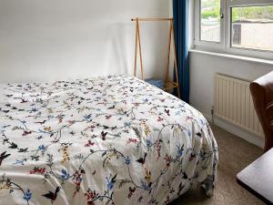 a bed with a white blanket with butterflies on it at Views Wood in Uckfield