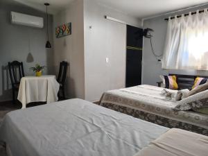 a bedroom with two beds and a table and a window at Urca do Tubarão in Touros