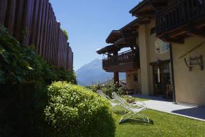 two lawn chairs sitting in the grass next to a building at B&B Petit in Sauze dʼOulx