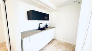a kitchen with white cabinets and a sink at Studio Premium Climatisé in Avallon