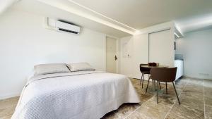 a white bedroom with a bed and a table at Studio Premium Climatisé in Avallon