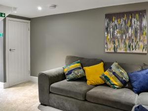 a living room with a gray couch with colorful pillows at Doodles Holiday Home in Eyemouth