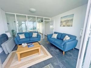 a living room with two blue couches and a coffee table at Chacewater in Newquay