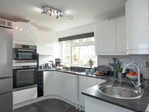 a kitchen with white cabinets and a sink and a window at Chacewater in Newquay