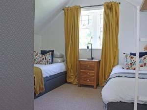 a bedroom with two beds and a window with yellow curtains at Deerview Lodge - Uk51044 in Bonvilston +10 photos