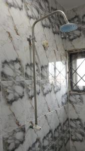 a shower in a bathroom with a stone wall at BP Aura Stay in Akitan