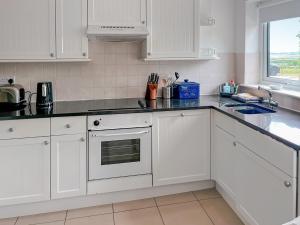a white kitchen with white cabinets and a window at Mistletoe No3 -Uk49252 in Althorne