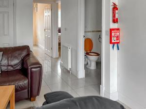 a living room with a leather chair and a toilet at Mistletoe No3 -Uk49252 in Althorne