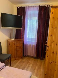 ein Schlafzimmer mit Fernseher und Fenster mit Vorhängen in der Unterkunft Wilhelmsthal in Wilhelmsthal