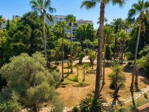 a park with palm trees and bushes at The Originals Résidence, Les Strélitzias in Juan-les-Pins