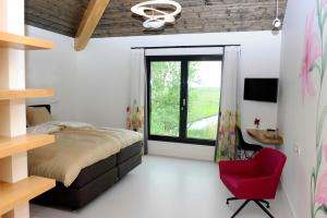 a bedroom with a bed and a red chair at als het golft in Roelofarendsveen