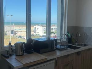 a kitchen counter with a microwave and a window at Studio Aloe horizon in Dunkerque