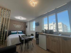 a bedroom with a bed and a kitchen with a table at Studio Aloe horizon in Dunkerque