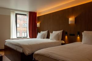 a hotel room with two beds and a window at Hotel The Exchange in Amsterdam