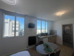 a room with a table and a desk with a window at Studio Aloe horizon in Dunkerque