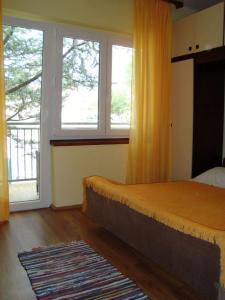 a bedroom with a bed and two windows and a rug at Apartman Marija Krok in Baška