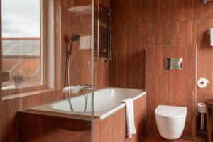 a bathroom with a bath tub and a toilet at Hotel The Exchange in Amsterdam
